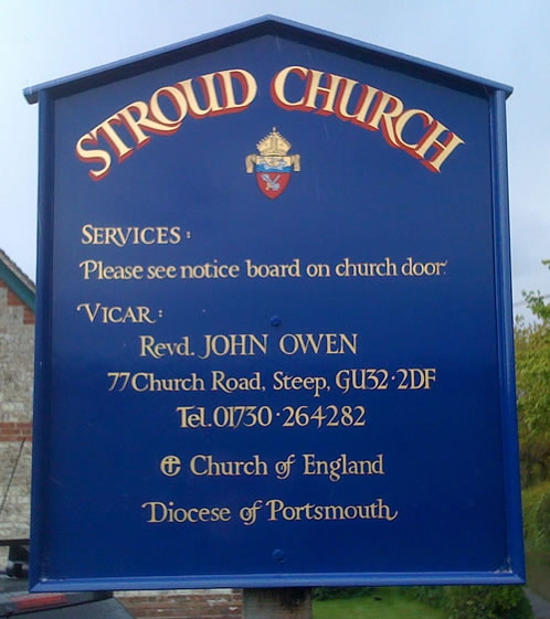 Church notice board with heraldic badge and gold lettering