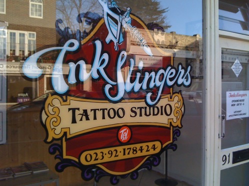 Tattooist glass window signwritten in reverse by hand