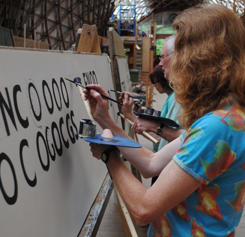 Students hand painting letters at a signwriting class