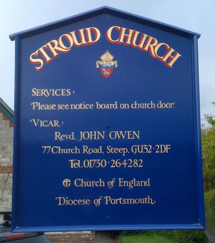 Church notice board with heraldic badge and gold lettering