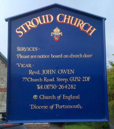 Church notice board with heraldic badge and gold lettering