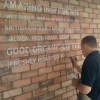 Wayne Osborne Signwriting a display wall sign